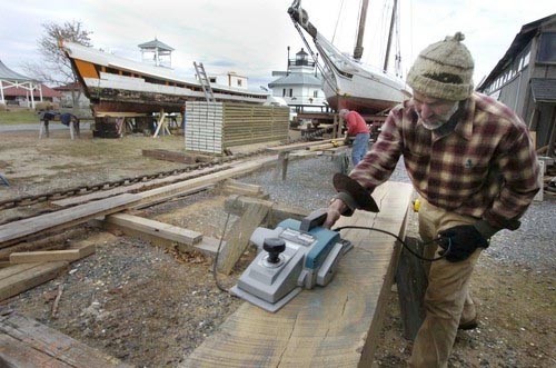 Skipjack in restoration mode - Mike Vlahovich with a planer on Caleb W. Jones © SW